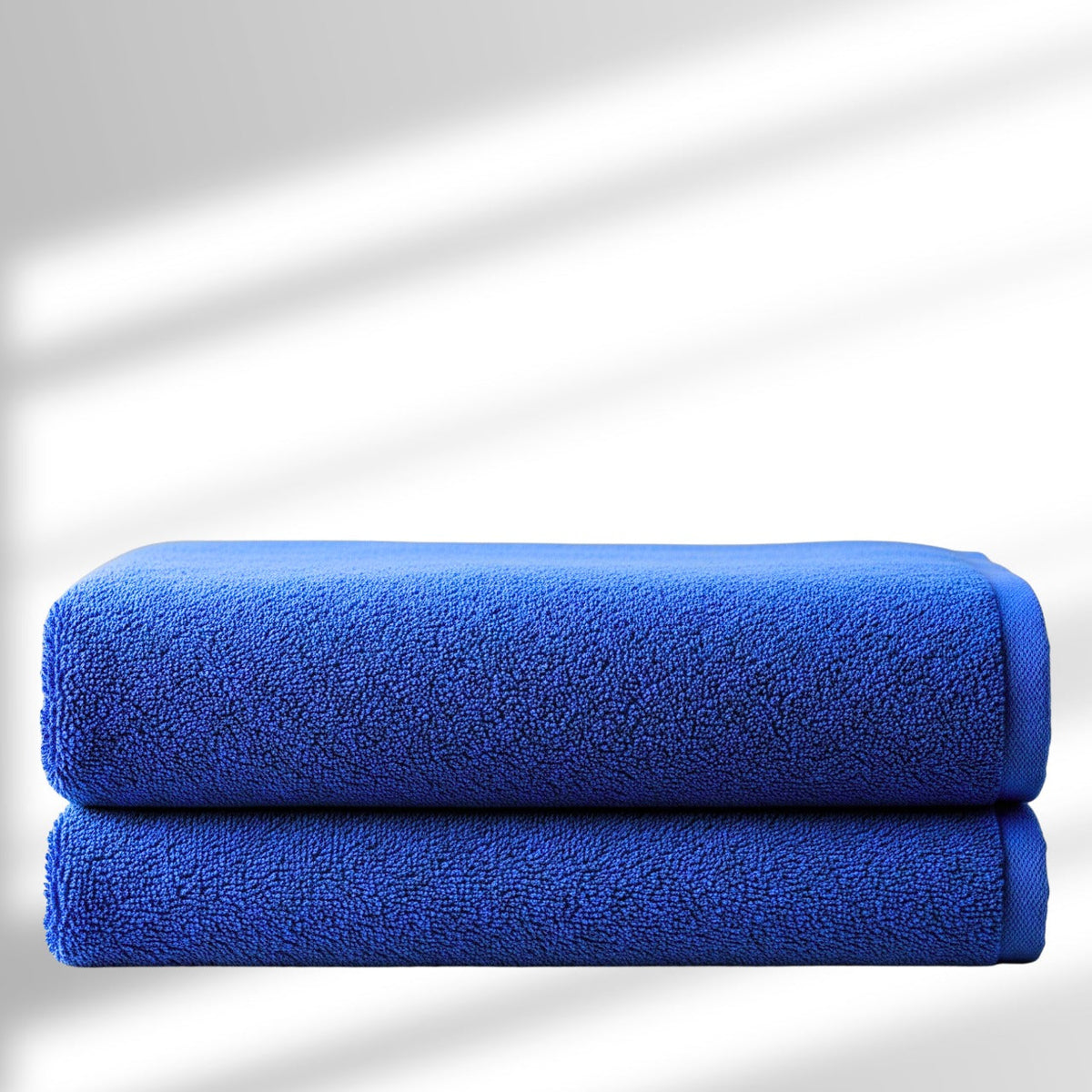 Two blue towels stacked on a white background